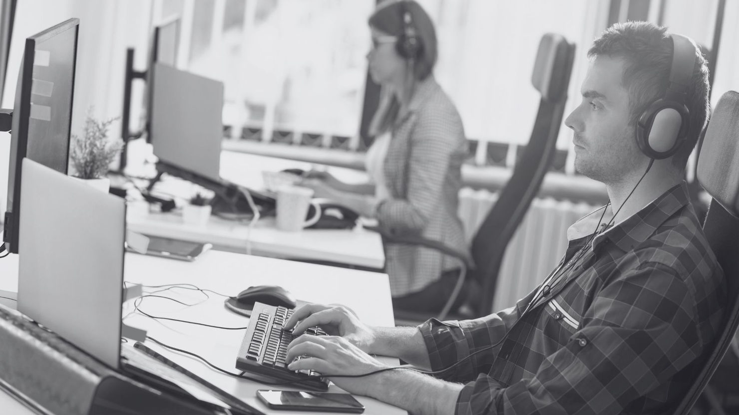 Focused programmer and colleague working at computers